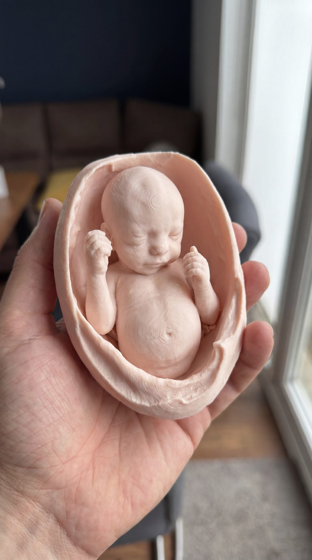 Hand holding a 3D printed fetal keepsake figurine from ultrasound
